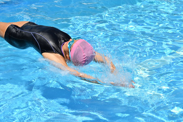 Japanese girl is swimming the backstroke in the pool