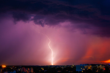 Lightning strikes storm over city purple light.