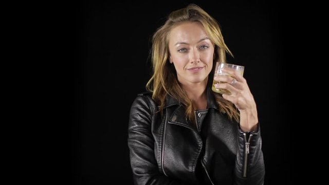 Tough and sexy woman in a black leather jacket, enjoying a drink.