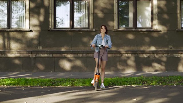 Woman rides electric scooter - Rented - Comes closer - Modern transportation gadget and popular futuristic device among young people