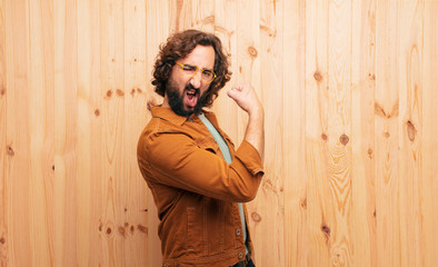 young bearded crazy man wearing cool clothes against wooden wall