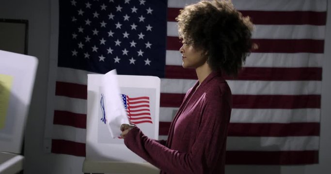 MS Young mixed-race woman tries to put her ballot paper down to vote but voting booths are removed each time by Caucasian people. Symbol of disenfranchisement with US flag backdrop. Hand-held 4K