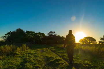 Hombre Caminando Hacia la Casa de Campo al Atardecer