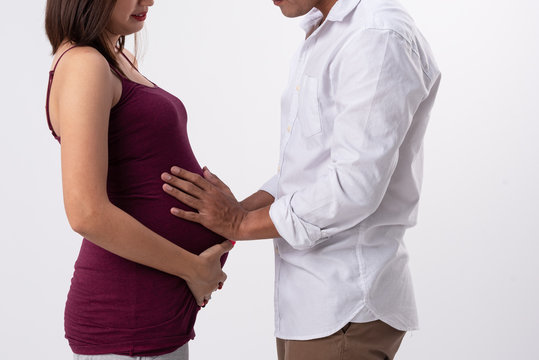 Close up of pregnant belly ,beautiful expectant tander lovely mother and father stand and hold ultrasound babu film put on belly.Waiting for birth of baby together.both feel happy.