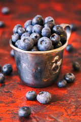 Blueberries in a metal mug on the orange background 