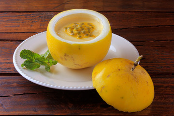 dessert Passion fruit mousse in the peel of the fruit, on plate over rustic wooden table