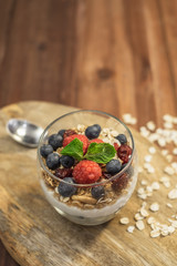 Healthy yogurt grain and berries dessert glass on top of a wooden tray on wood surface background.