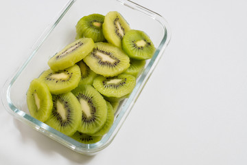 Many kiwi slices are placed in a glass crisper. Kiwifruit slices without peel.