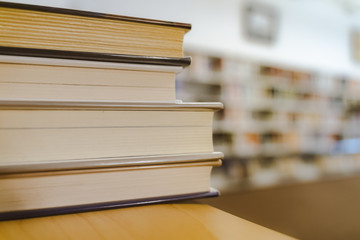 Book in library with old open textbook, stack piles of literature text archive on reading desk, and aisle of bookshelves in school study class room background for academic education learning concept