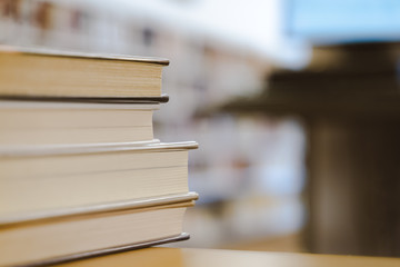 Book in library with old open textbook, stack piles of literature text archive on reading desk, and aisle of bookshelves in school study class room background for academic education learning concept