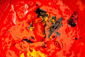 Closeup beautiful red color of oil paint mix with black and other colorful background.