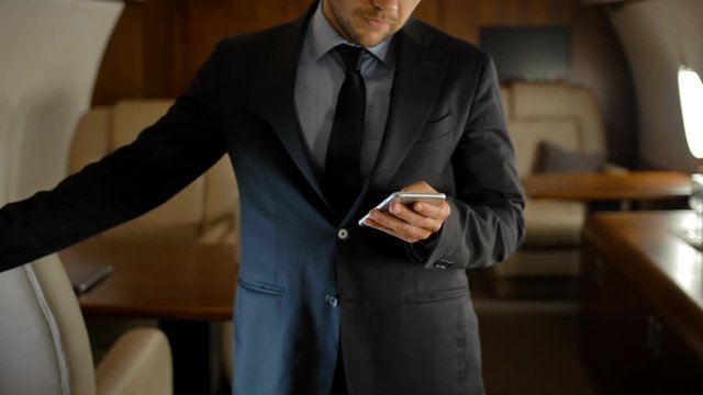 Entrepreneur with smartphone inside of private jet.