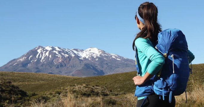 Travel lifestyle - active woman hiker backpacking on hike looking at mountain she is ready to conquer. Wanderlust travel vacation concept with multiracial asian caucasian model.