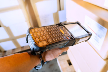 worker hand holding bar code scanner with scanning laser on package box.
