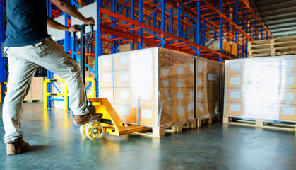 warehouse worker working with hand pallet truck and cargo shipment pallet at distribution warehouse supply chain package boxes on wooden pallet cargo export for transportation. - obrazy, fototapety, plakaty