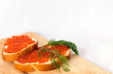 Sandwich with red salmon caviar on a cutting Board on white background