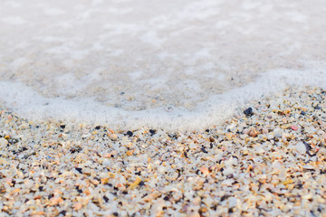 Wave bubbles on the beach with small shells