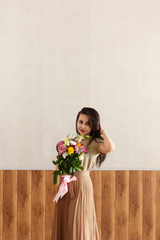 Beautiful middle-eastern girl with a bouquet of flowers in hands. Young attractive female with flowers. Portrait of charming, pretty girl holding flowers bouquet