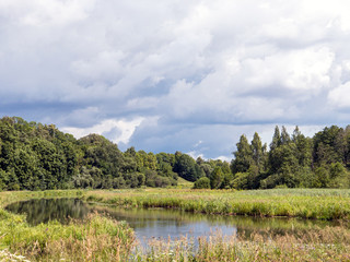 beautiful landscape with small river and cloudy sky on sunny summer day
