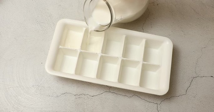 Putting fresh milk into ice cube tray