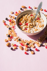 wholegrain flakes with berries and milk on pink. Healthy tasty breakfast cornflakes with blueberries, raspberries and red currant.Multigrain wholewheat healthy cereals with fresh berry.