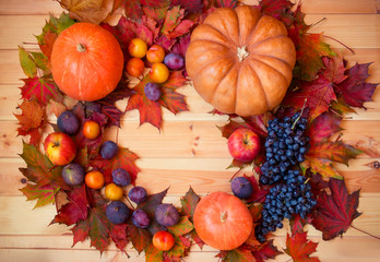 Frame made of pumpkins, autumn leaves and fresh fruits on wooden background.