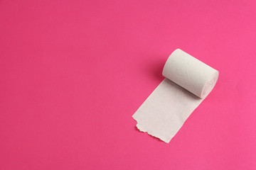 roll of rough white toilet paper on pink background, close-up, copy space, concept of stomach problems or diarrhea