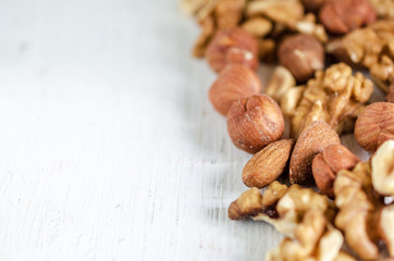 Assorted of nuts on white wooden table. Peanut, hazelnuts, walnuts, almonds.