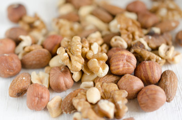 Assorted of nuts on white wooden table. Peanut, hazelnuts, walnuts, almonds.
