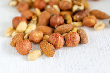Assorted of nuts on white wooden table. Peanut, hazelnuts, walnuts, almonds.