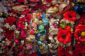 Fototapeta na wymiar Bouquets of artificial flowers are sold at the fair. Corollas of colored small flowers. Closeup of national decorations and accessories for clothing.