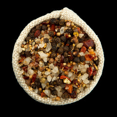 Obraz na płótnie Canvas A mixture of peppers and salt in a bag isolated on a black background. View from above. Seasoning on isolate. Dry spices.