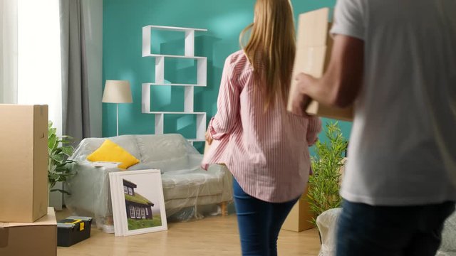 A young couple brings boxes to a new apartment and gives a high five