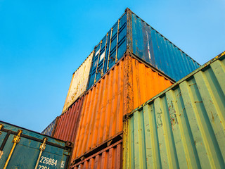 High Stack Towering Containers Box Up To The Blue Sky in Logistic Warehouse. Concept of Cargo Transhipment in Business for Economic Growth.