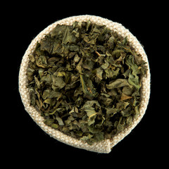 Dry green herbs in a bag isolated on a black background. View from above. Seasoning on isolate. Dry spices.