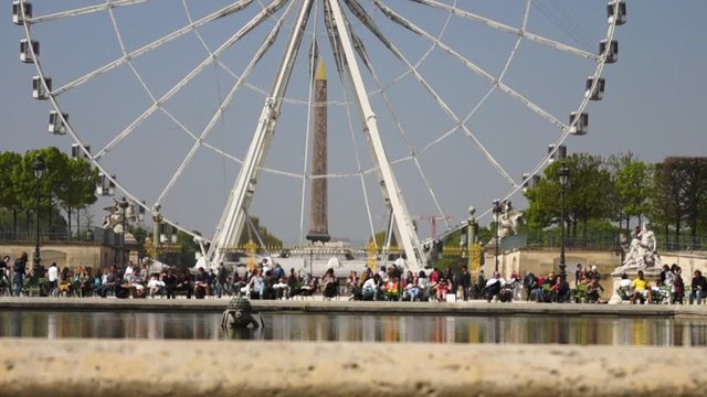 Time lapse of people in front if a ferris wheel.