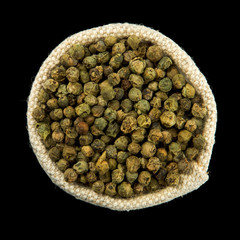 Dry green pepper in a bag isolated on a black background. View from above. Seasoning on isolate. Dry spices.