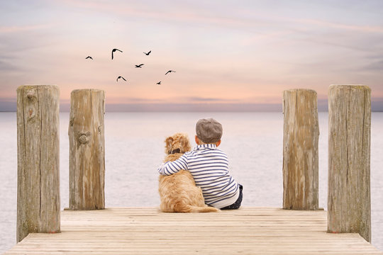 kleiner Junge umarmt seinen Hund am Steg am See
