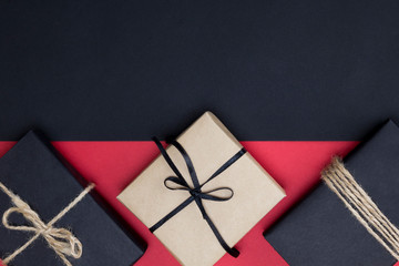Fototapeta premium Gifts in craft and black paper on red background. Shopping, sale, Black Friday, Christmas gift concept. Close-up, mock up, copy space, layout design, top view, flat lay, horizontal border