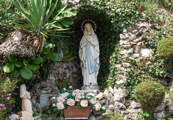 stone chapel with flowers and candles with Our Lady of Lourdes