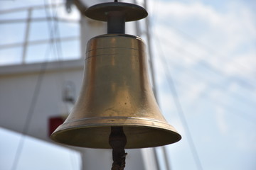 A vintage bronze ship bell hanging from the ship's deck	