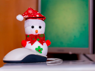 Toy snowman near computer. Working in the office at the computer. Modern computer technologies_