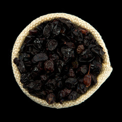 Dried barberry in a bag isolated on a black background. Seasoning on isolate. View from above. Dry spices.