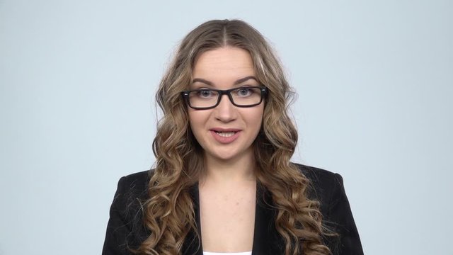 Businesswoman is reporting and tells a lot of interesting news against grey background, slow motion