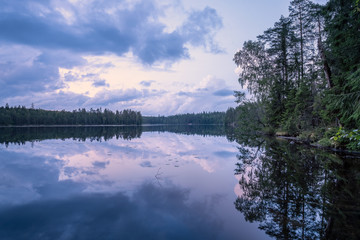 Scenic summer night landscape with mood light and beautiful reflections at lakeside in Finland.