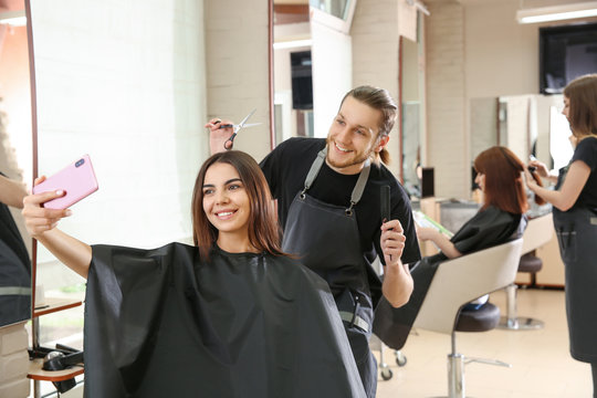 Young woman taking selfie with her hairdresser in salon