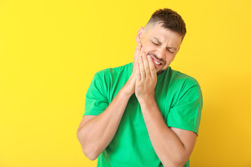 Man suffering from toothache against color background