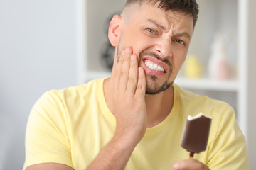 Man with sensitive teeth and cold ice-cream at home