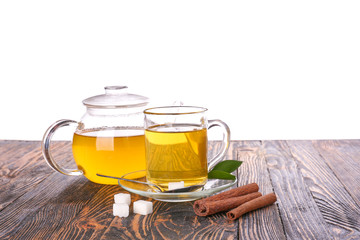 Tasty tea with sugar and cinnamon on wooden table against white background