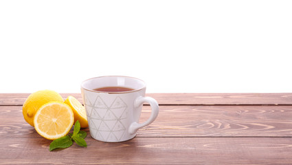 Obraz na płótnie Canvas Cup of tasty tea with mint and lemon on wooden table against white background